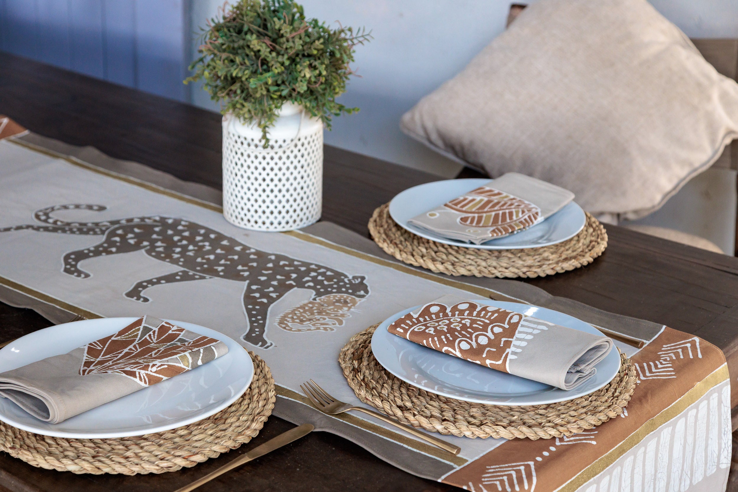 Dining table setting with patterned placemats and napkins, featuring leopard
