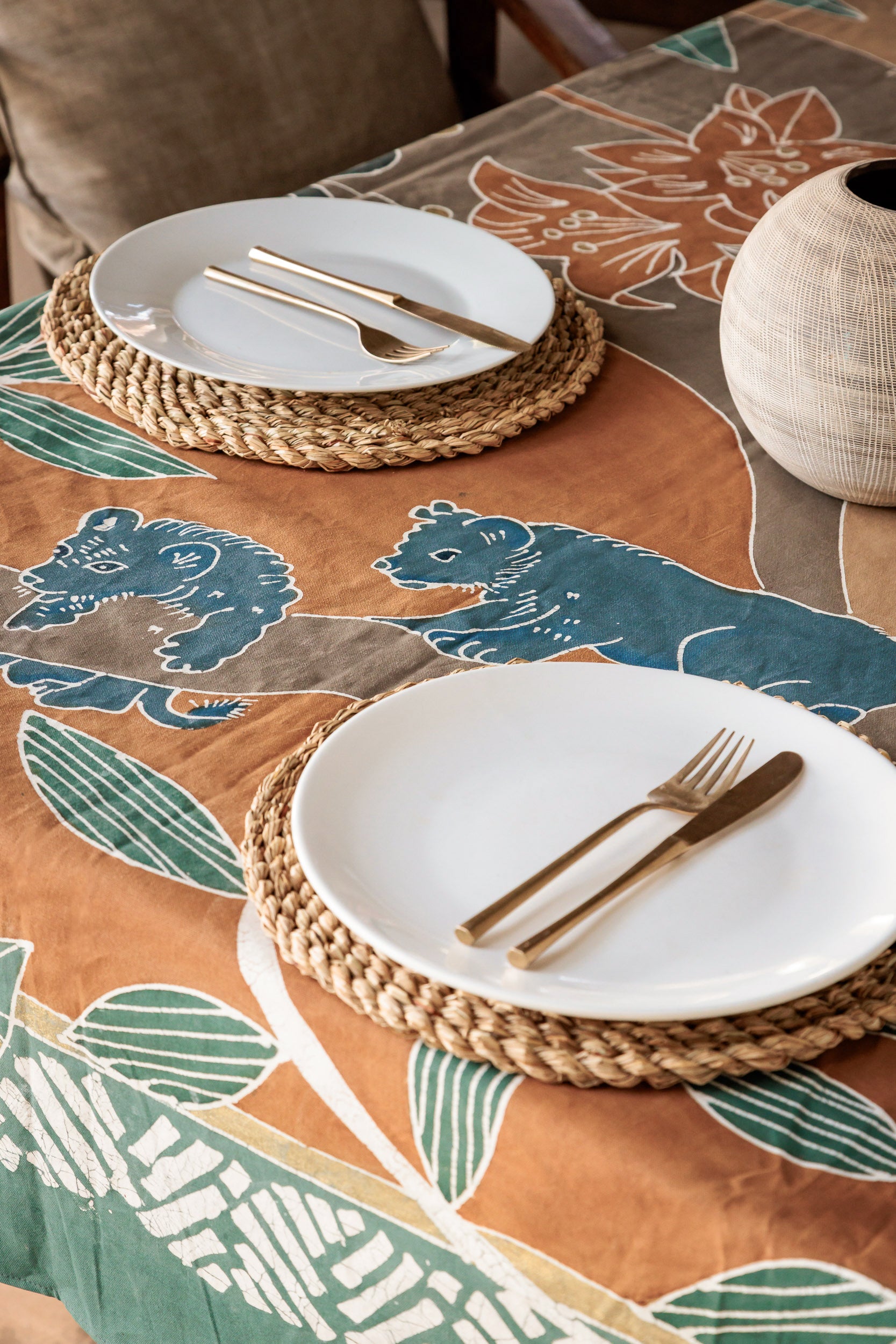 Table setting featuring a handcrafted hand painted lion table cloth in warm colours.
