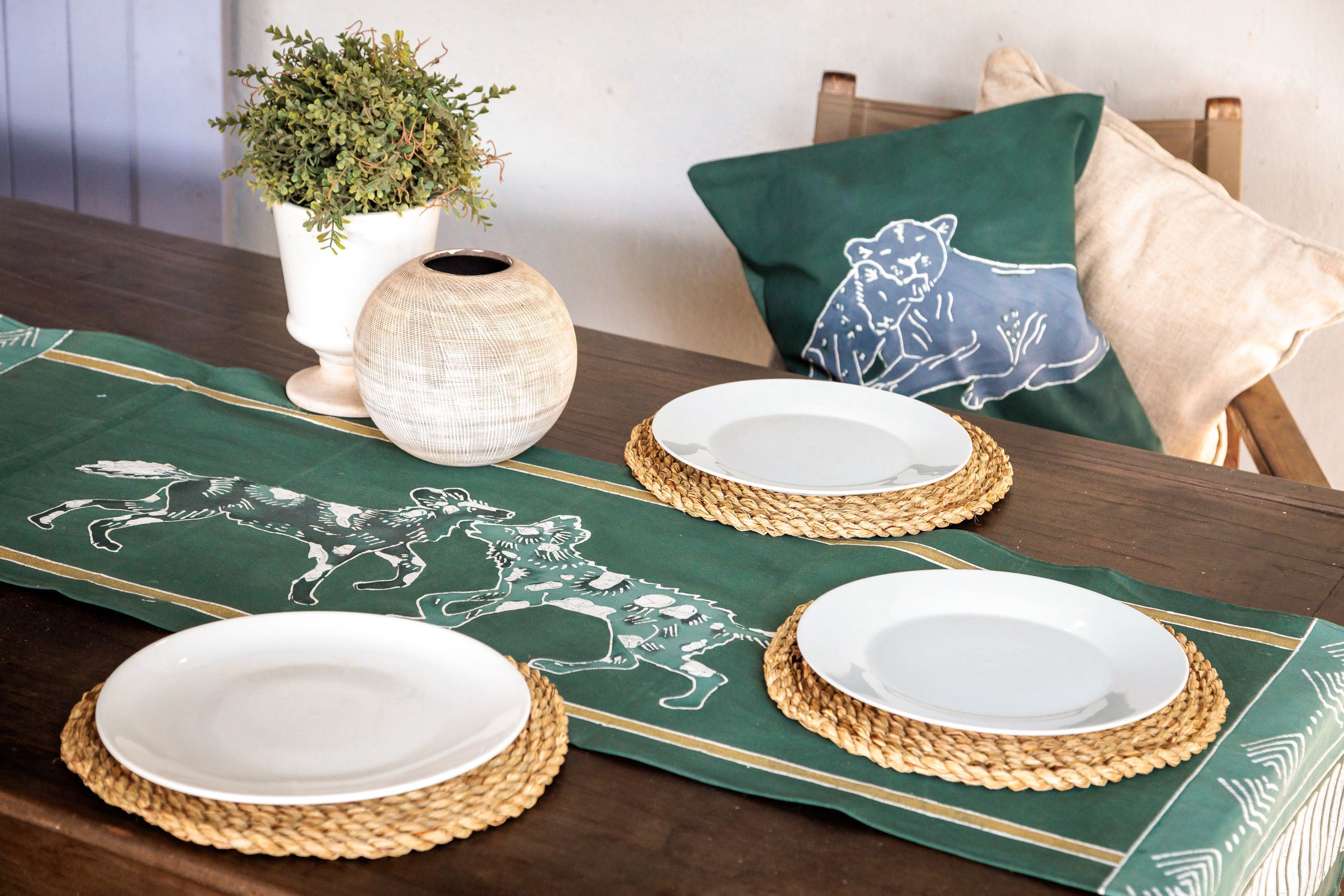 Table setting , green table runner featuring wild dogs, conservation support.