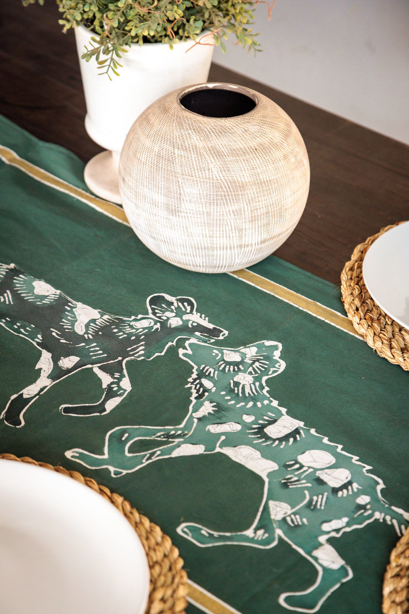 Green table runner with wild dog animal prints, in support of zambian carnivore programme.