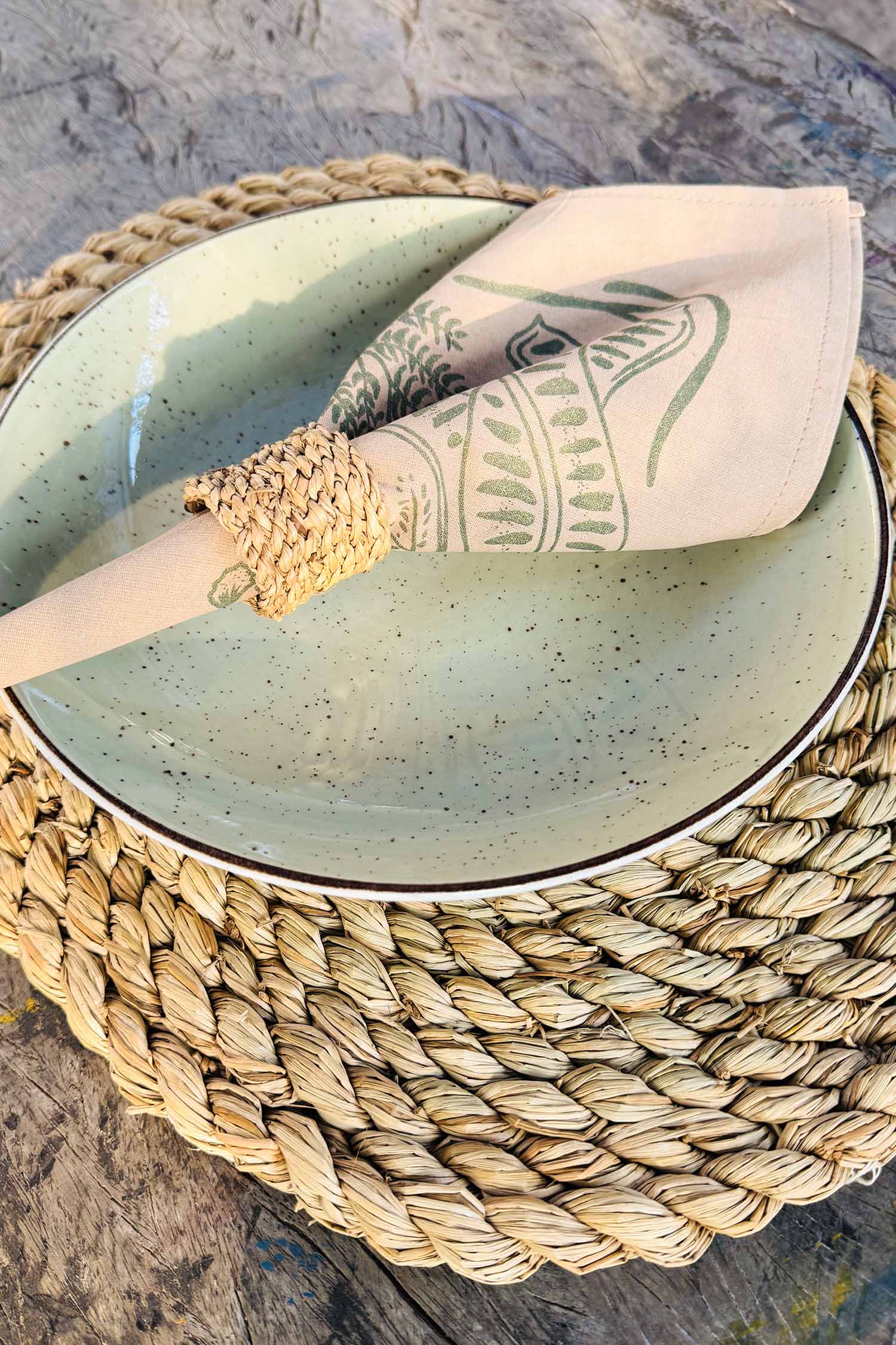 Close-up of beige cotton napkin with hand-printed green leaf design, ethically handcrafted in Zambia for sustainable, eco-friendly dining decor and artisan home styling.