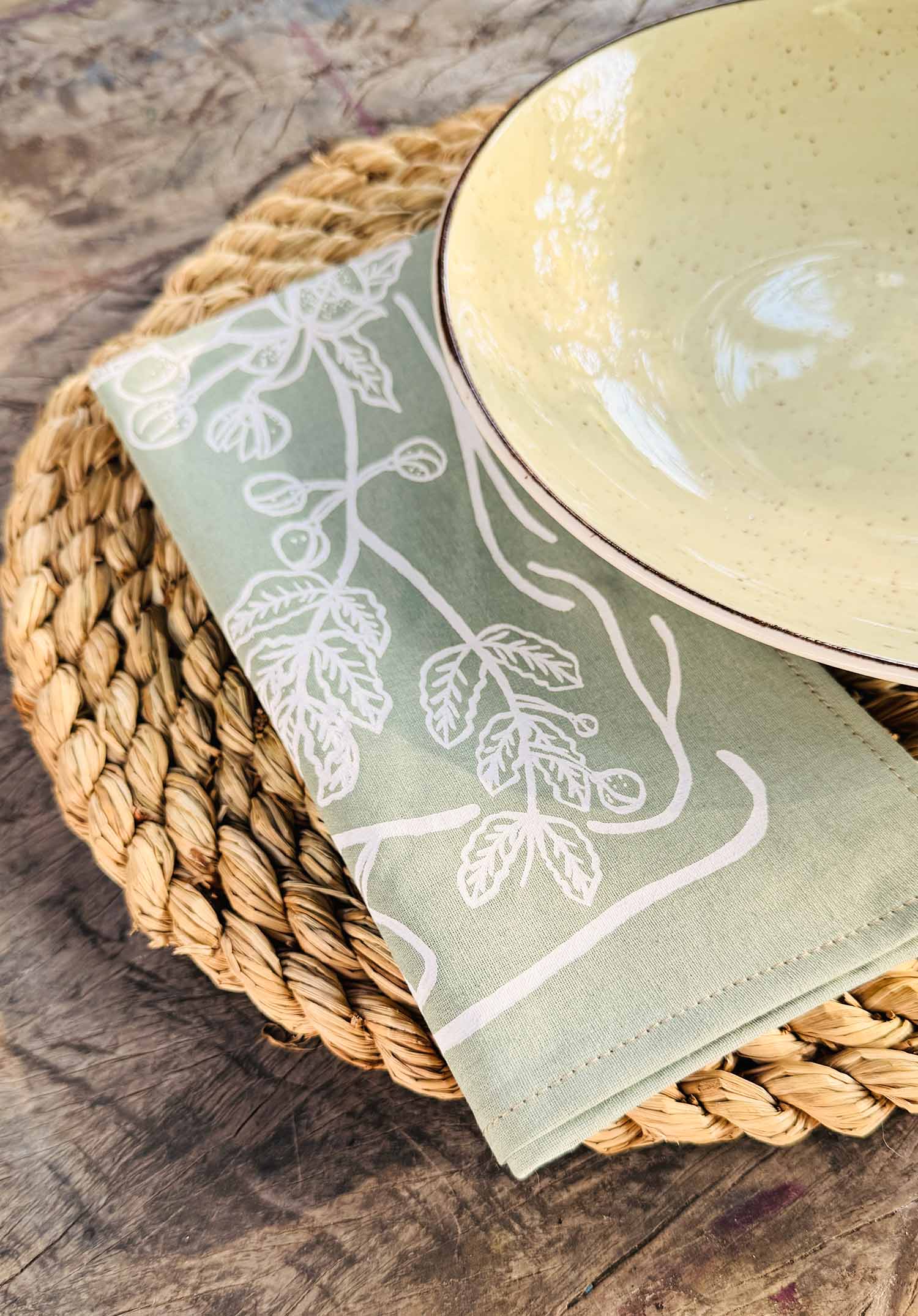 Detailed view of sage green cotton napkins with delicate hand-printed leaf motifs, ethically handcrafted in Zambia for sustainable, eco-friendly dining decor and artisan tableware.
