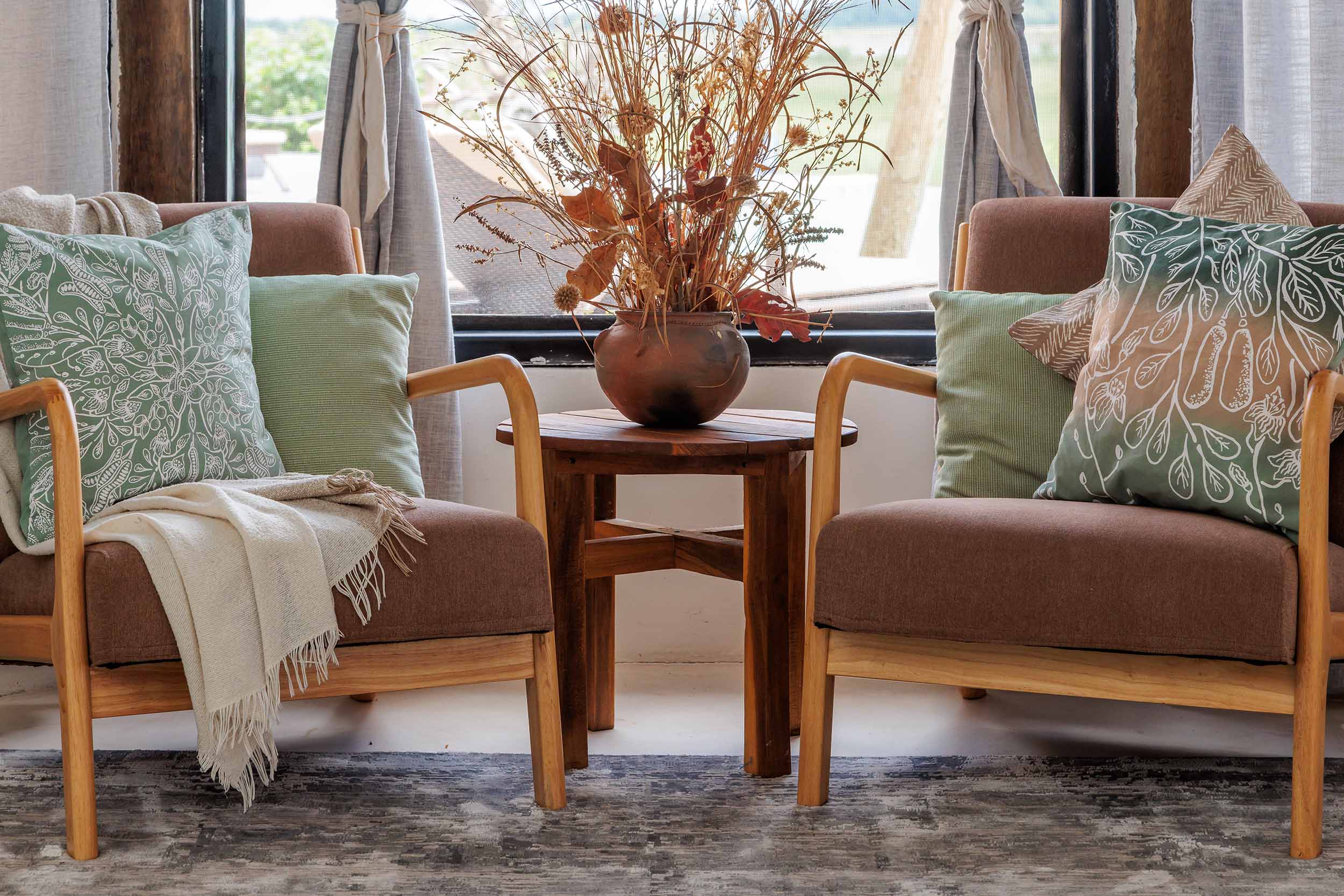 Two green cotton pillows with bold Sausage Tree and symmetrical leaf patterns, ethically handcrafted in Zambia, perfect for adding sustainable, eco-friendly style to living room or bedroom interiors.