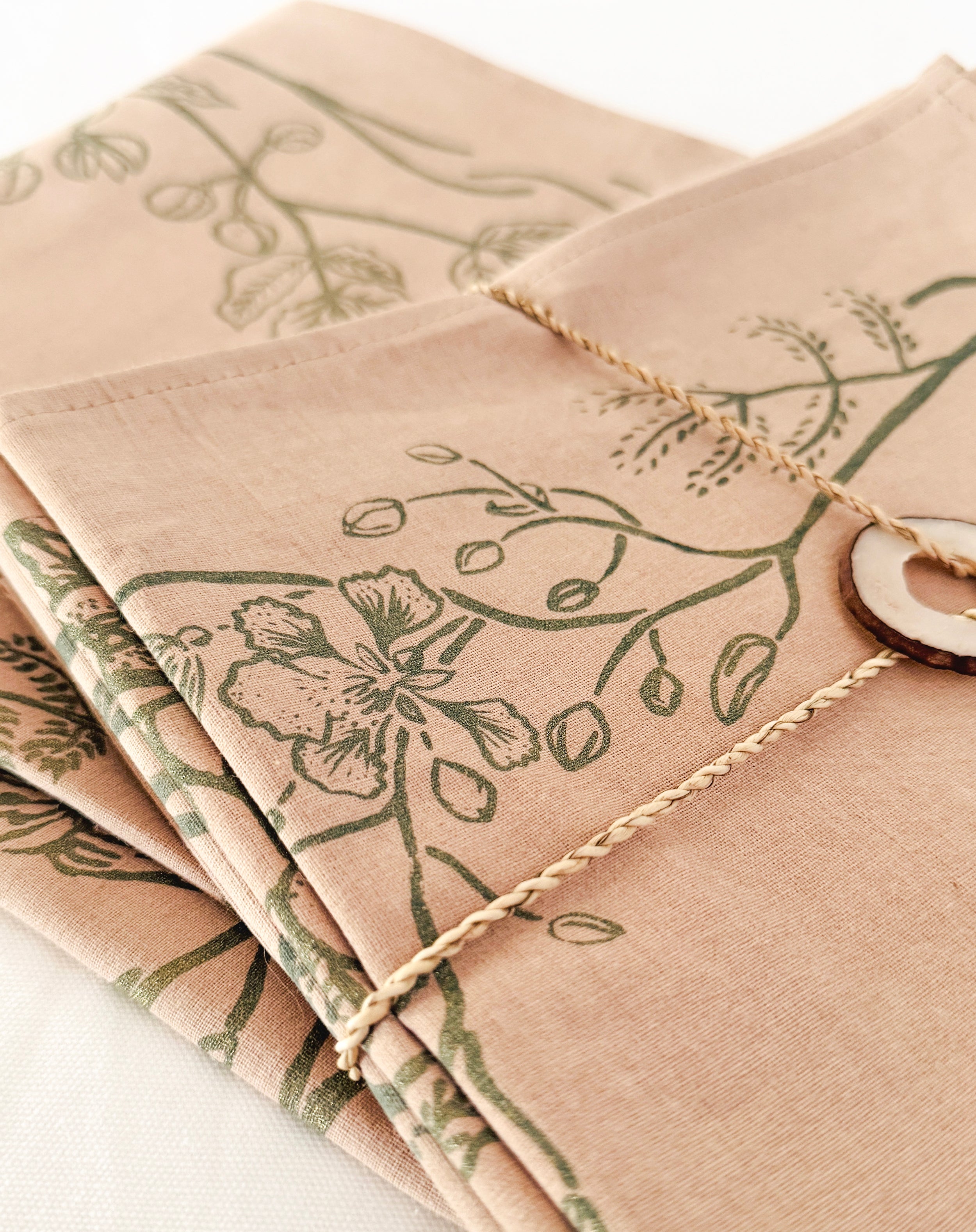 Close-up of beige cotton napkin featuring subtle green leaf print and natural texture, ethically handcrafted in Zambia for sustainable, eco-friendly dining and artisan home decor.