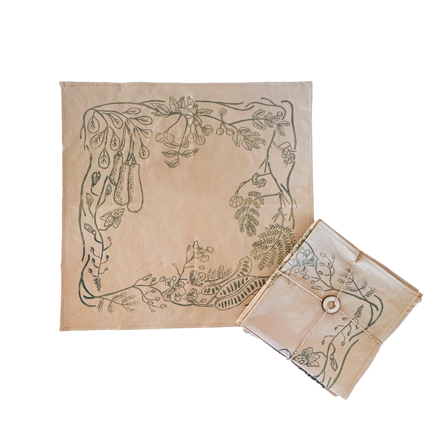Beige cotton napkins with subtle green leaf print, neatly folded on a natural wood surface, ethically handcrafted in Zambia for sustainable, eco-friendly dining and artisan home decor.