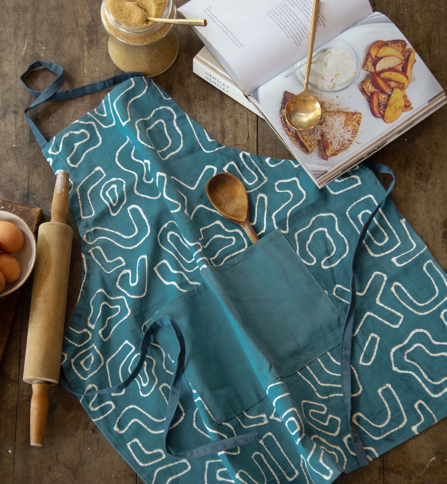 Add some African sustainable style with this teal apron adorned with a squiggle pattern.