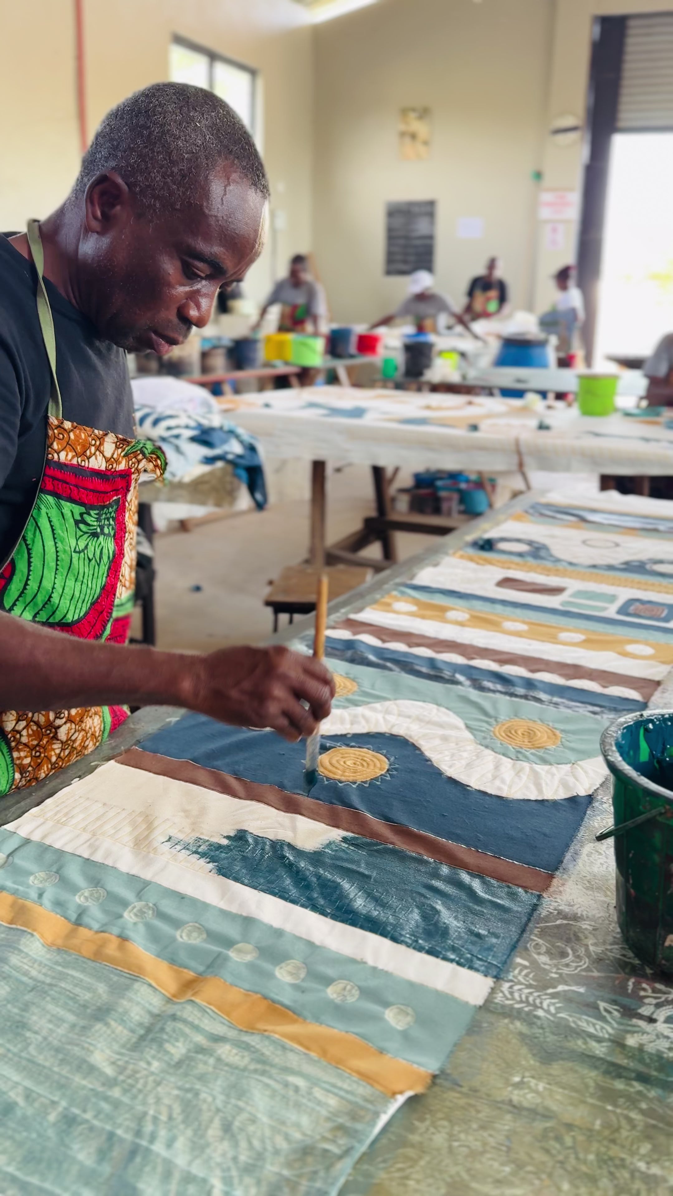 Artisan hand-paints ethically handcrafted cotton textiles in Zambia using sustainable techniques for eco-friendly home decor and fair trade gifts.