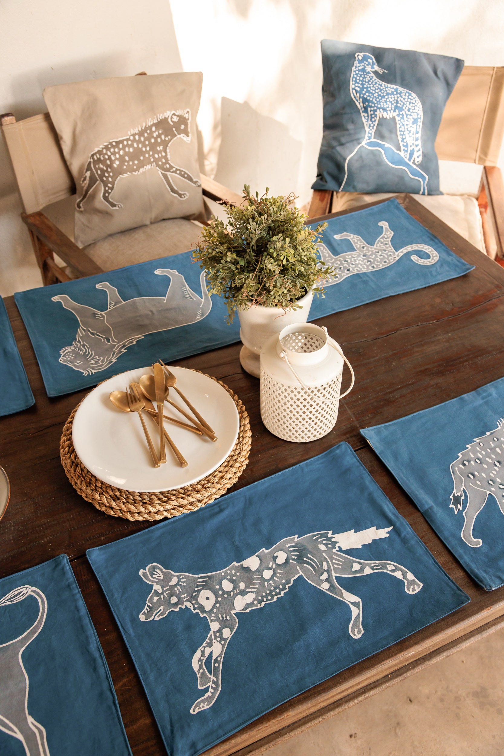 Table setting with blue placemats featuring safari animal designs that are hand painted on batik. Made in Africa