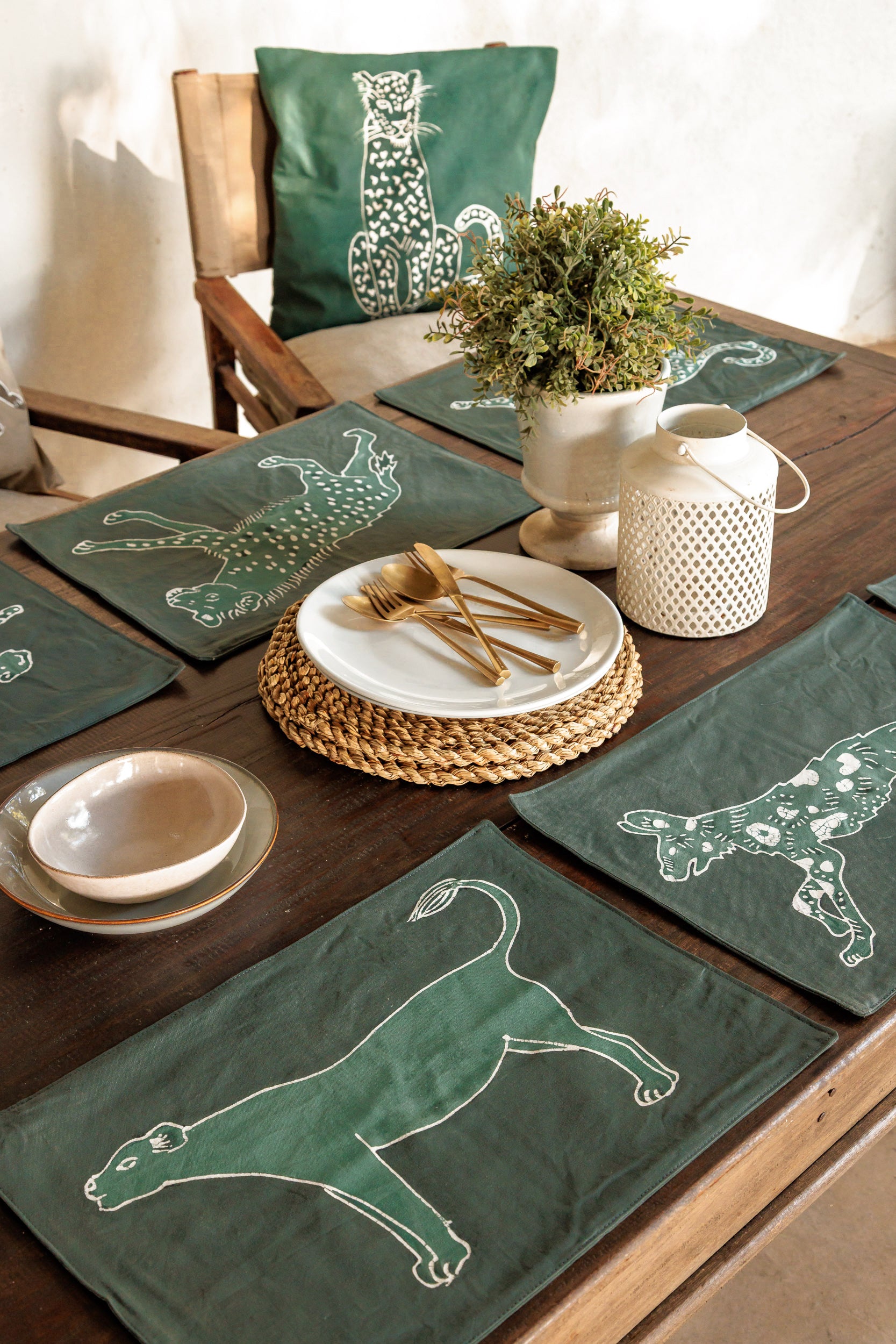 Dining table set with green placemats featuring wild animal designs handcrafted batik.