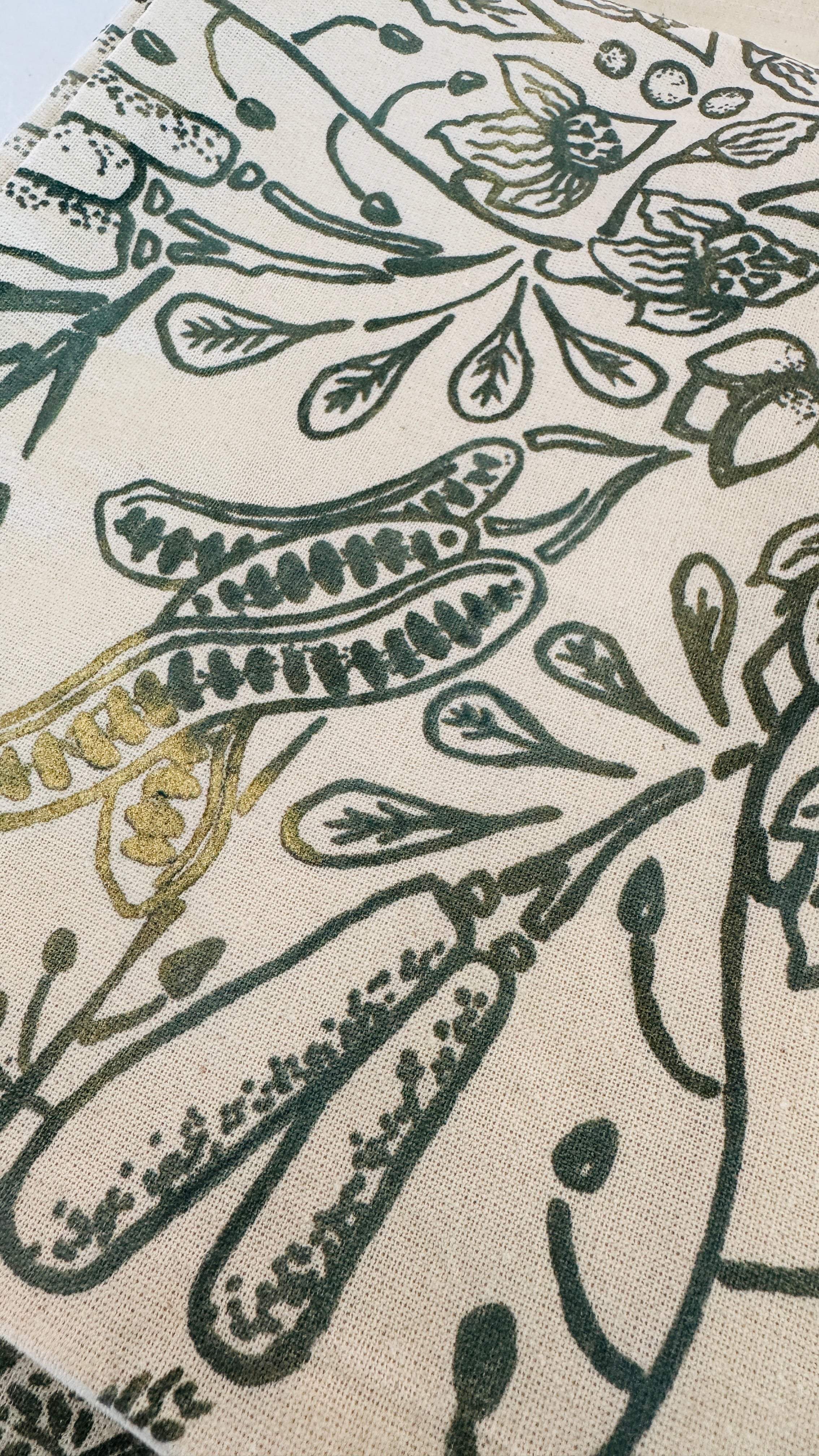 Close-up of beige cotton cushion cover with detailed hand-printed green leaf patterns, ethically handcrafted in Zambia for sustainable, eco-friendly living room or bedroom decor and artisan interiors.
