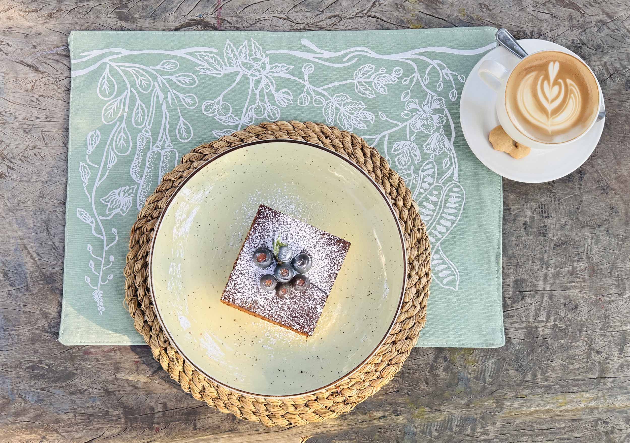 Set of sage green cotton table mats featuring delicate hand-printed leaf designs, ethically handcrafted in Zambia for sustainable, eco-friendly dining room decor and artisan interiors.
