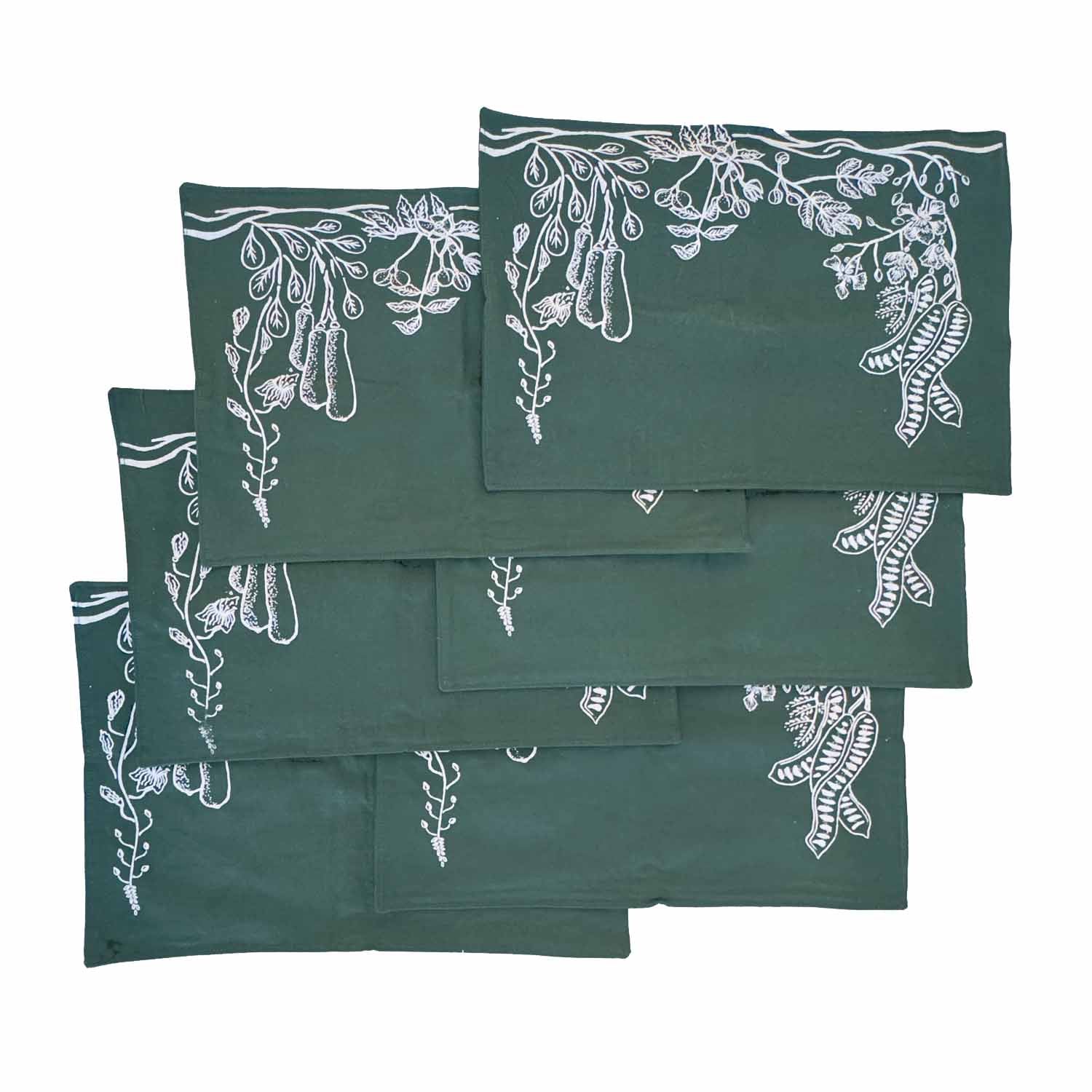 Forest green cotton table mats with subtle leaf designs, styled on a rustic wooden table, ethically handcrafted in Zambia for sustainable, eco-friendly dining decor and artisan interiors.
