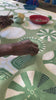 Artisan carefully hand-painting an african motif onto cotton fabric in a sunlit workshop, showcasing sustainable, eco-friendly, and ethically handcrafted textile techniques from Zambia for unique home decor and fair trade gifts.
